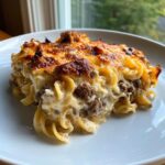 A close-up serving of baked Salisbury steak pasta casserole with a rich, browned cheese crust.