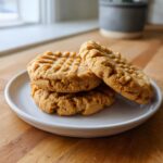 Three thick, softest peanut butter cookies with classic crosshatch fork marks stacked on a small white plate.