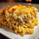 Close-up of a generous slice of sour cream beef noodle casserole topped with melted, browned cheddar cheese.