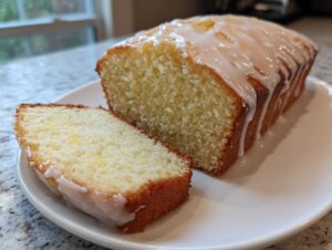 A slice cut from a moist sourdough discard lemon loaf topped with a white lemon glaze.