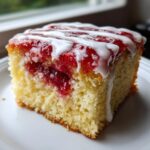 Close-up of a slice of strawberry poptart sheet cake showing moist yellow cake, bright red strawberry filling, and white vanilla icing drizzle.