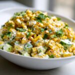 A close-up of street corn creamy cucumber chicken salad featuring charred corn, diced cucumber, and creamy dressing, topped with cilantro.
