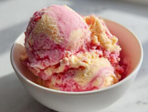 Close-up of two scoops of swirled pink and yellow summer sherbet in a white bowl.