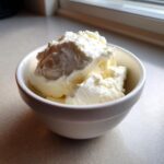 A close-up of thick, creamy homemade yogurt scooped into a small white bowl, ready to eat.