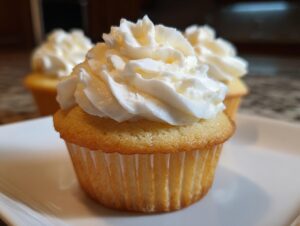 Close-up of a moist vanilla cupcake from scratch topped with a swirl of white buttercream frosting.