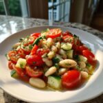 A bright white bean salad featuring white beans, halved cherry tomatoes, and chopped cucumber, dressed and garnished with dill.