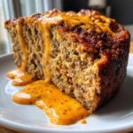 A thick slice of moist Buffalo chicken meatloaf generously topped and drizzled with a vibrant orange, spicy glaze.