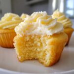 Close-up of a Military spouse appreciation cupcake with a bite taken out, showing moist yellow cake and creamy white frosting.