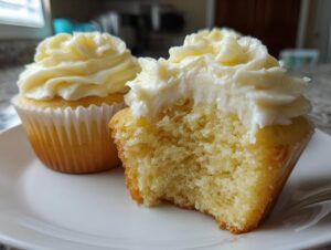Close-up of a Military spouse appreciation cupcake with a bite taken out, showing the moist yellow cake and creamy white frosting.