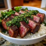 Close-up of perfectly seared Wagyu beef steak chimichurri bowl, featuring medium-rare slices over rice and greens.